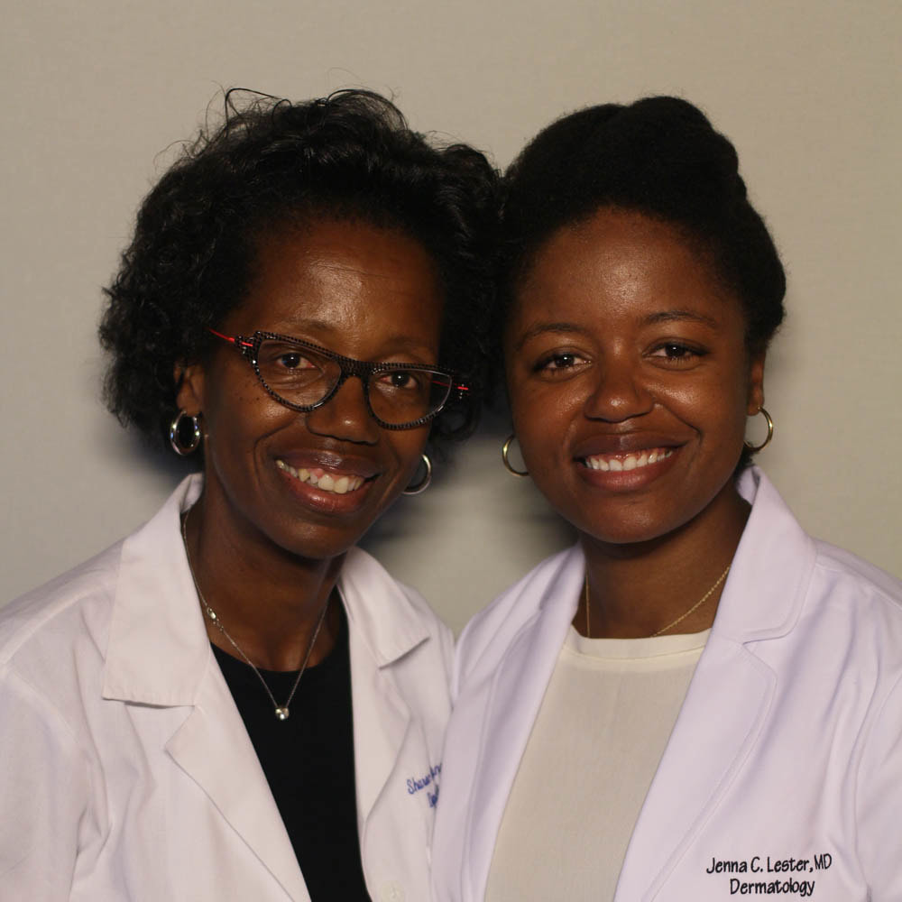 A Black mother and daughter wear their doctors' coats and smile at the camera, heads inclined toward each other.